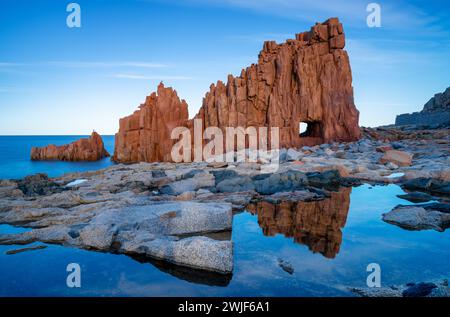 Une vue des roches rouges d'Arbatax avec des reflets dans les bassins de marée au premier plan Banque D'Images