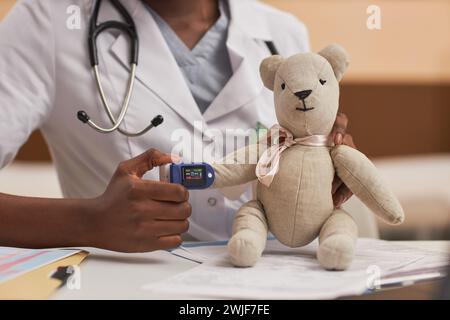 Gros plan d'un médecin méconnaissable mettant un oxymètre de pouls sur un ours en jouet expliquant le check up Banque D'Images