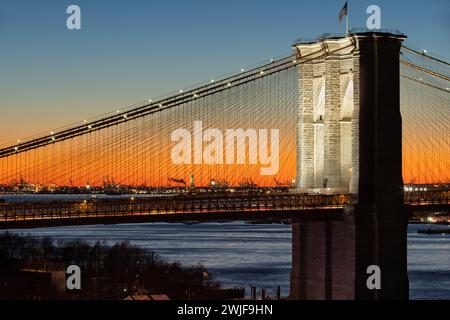 Illuminé le pont de Brooklyn au coucher du soleil et la Statue de la liberté au loin. Gros plan sur les sites historiques de New York Banque D'Images