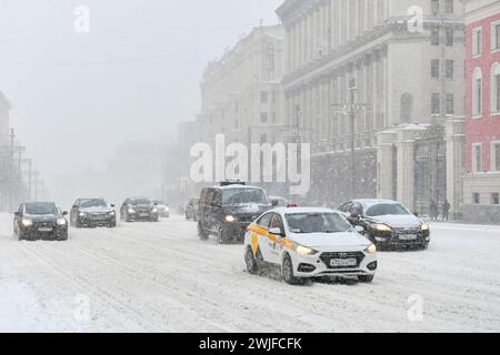 Moscou, Russie. 15 février 2024. Les véhicules circulent dans une rue au milieu des chutes de neige à Moscou, Russie, le 15 février 2024. Une forte neige a frappé Moscou jeudi. Crédit : Cao Yang/Xinhua/Alamy Live News Banque D'Images