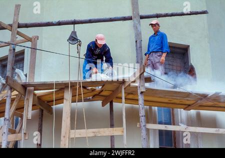 Roumanie, Bucarest, chantier de construction d'un nouveau projet de logements. Les ouvriers de la construction coupent les briques à la taille voulue. Banque D'Images
