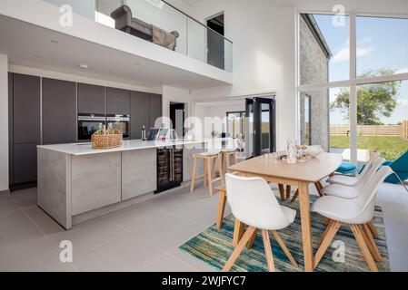 Cambridgeshire, Angleterre - 1er mai 2018 : cuisine ouverte moderne et meublée, salle à manger avec portes à deux battants et bar à petit-déjeuner., Banque D'Images