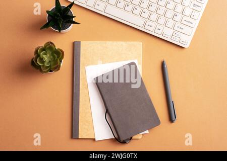 Bureau avec bloc-notes, stylo, clavier et plantes succulentes sur table beige. Vue de dessus, pose à plat. Banque D'Images