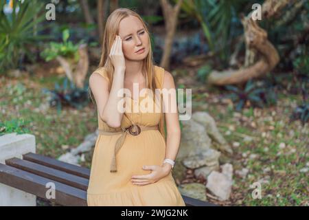 Une femme enceinte éprouve un moment d'inconfort, aux prises avec un mal de tête pendant la grossesse, soulignant le défi commun et la nécessité de Banque D'Images