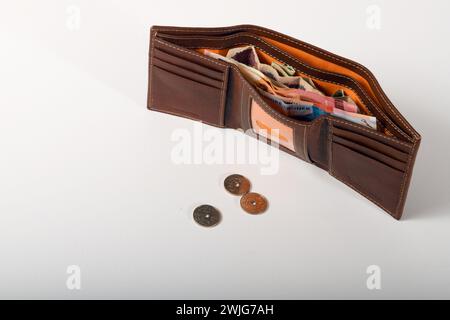 Portefeuille marron rempli de billets d'argent. Trois pièces norvégiennes sur la table. .Fond blanc. Copiez l'espace vers la gauche. Banque D'Images
