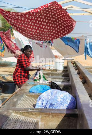 Boa Vista, cap-Vert- 22 mars 2018 : harmonie avec la nature : femme lavant des vêtements au bord de la mer. Banque D'Images