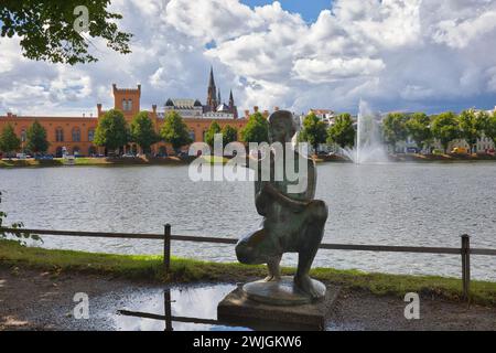 Allemagne, Mecklenburg-Vorpommern, Schwerin - 26 juillet 2023 : Der Junge mit der Taube est une sculpture en bronze située sur la promenade de Pfaffenteich. Banque D'Images