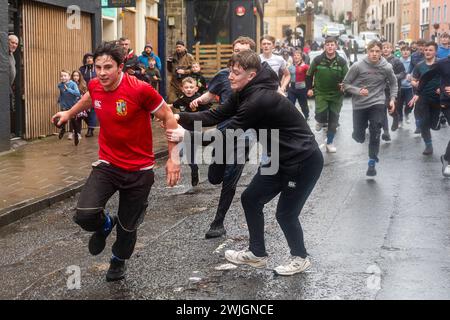 Les jeunes prennent part à la 'Hand BA' annuelle qui se joue dans la ville écossaise de Jedburgh. Traditionnellement, le premier match se jouait avec la tête d’un Anglais, les rubans sur le ballon symbolisant ses cheveux. Les équipes (Uppies et Doonies) sont choisies en fonction de leur lieu de résidence – les Uppies sont ceux nés au sud et les Doonies au nord de la Croix du marché. Crédit : Euan Cherry Banque D'Images