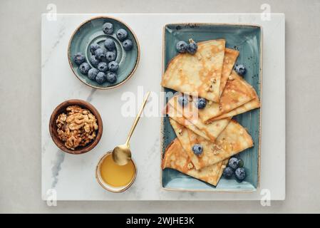 Crêpes fines, crêpes maison sur une assiette avec myrtille, miel et noix, vue de dessus Banque D'Images