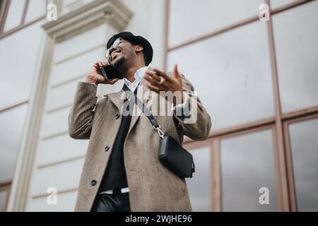 Homme d'affaires élégant appréciant une conversation allégée sur téléphone intelligent à l'extérieur. Banque D'Images