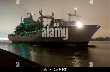 15 février 2024, Mecklembourg-Poméranie occidentale, Warnemünde : avec ses lumières éteintes, le navire ravitailleur de 174 mètres de long de la marine allemande « Bonn » quitte l'arsenal naval après des réparations et se dirige vers la mer Baltique. Le navire de la marine y est arrivé au début de la semaine dernière parce que le joint de l'arbre d'entraînement a dû être réparé en cale sèche. Selon la marine, le «Bonn» participe depuis le début de l'année à la mission OTAN «Force opérationnelle interarmées à très haut niveau de préparation maritime» sur le flanc nord de la mer du Nord et de la mer Baltique et dans l'Atlantique Nord. Photo : Bernd Wüstneck/ Banque D'Images