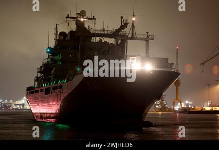 15 février 2024, Mecklembourg-Poméranie occidentale, Warnemünde : avec ses lumières éteintes, le navire ravitailleur de 174 mètres de long de la marine allemande « Bonn » quitte l'arsenal naval après des réparations et se dirige vers la mer Baltique. Le navire de la marine y est arrivé au début de la semaine dernière parce que le joint de l'arbre d'entraînement a dû être réparé en cale sèche. Selon la marine, le «Bonn» participe depuis le début de l'année à la mission OTAN «Force opérationnelle interarmées à très haut niveau de préparation maritime» sur le flanc nord de la mer du Nord et de la mer Baltique et dans l'Atlantique Nord. Photo : Bernd Wüstneck/ Banque D'Images