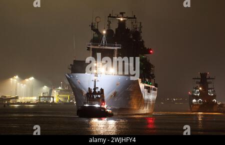 15 février 2024, Mecklembourg-Poméranie occidentale, Warnemünde : avec ses feux éteints, le navire de ravitaillement de la marine allemande, le « Bonn », long de 174 mètres, est remorqué hors de l'arsenal naval par un remorqueur après des réparations et se dirige vers la mer Baltique. Le plus gros navire de la marine y est arrivé au début de la semaine dernière parce que le joint de l'arbre d'entraînement a dû être réparé en cale sèche. Selon la marine, le «Bonn» a été déployé dans le cadre de la mission OTAN «Very High Readiness joint Task Force maritime» sur le flanc nord de la mer du Nord et de la mer Baltique et dans l'Atlantique Nord depuis le début Banque D'Images