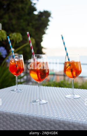 Trois spritz aperol avec des pailles sur une table blanche lors d'une soirée d'été dans un pub méditerranéen à côté de la plage Banque D'Images