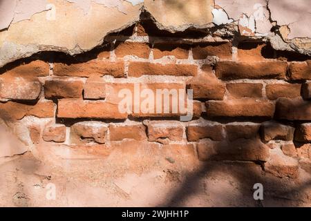Mur de briques avec plâtre tombé de vieille maison abandonnée gros plan comme fond grunge Banque D'Images