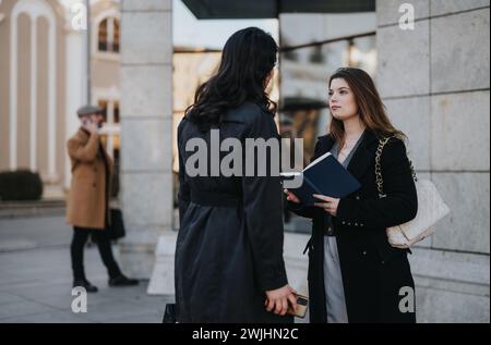 Deux femmes professionnelles s'engageant dans la conversation à l'extérieur près de l'immeuble de bureaux. Banque D'Images