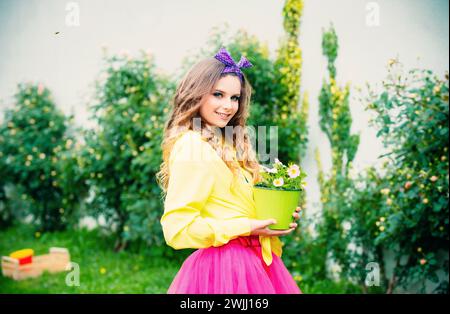 Adolescente jardinage. Jeune belle femme avec des pots de fleurs sur fond de nature verte. Concept de ressort. Banque D'Images