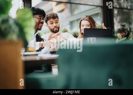 Trois collègues multiethniques collaborent sur la paperasserie dans un environnement de restaurant détendu, avec un accent sur le travail d'équipe et la stratégie d'entreprise. Banque D'Images