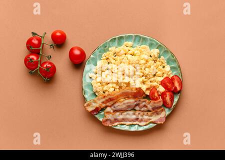 Assiette de savoureux oeufs brouillés avec du bacon sur fond brun Banque D'Images