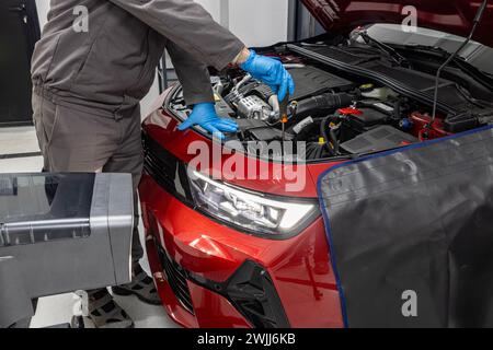 Réglage des phares de la voiture dans le service de voiture. l'ouvrier d'atelier de réparation de voitures vérifie et ajuste les phares du système d'éclairage d'une voiture. Banque D'Images