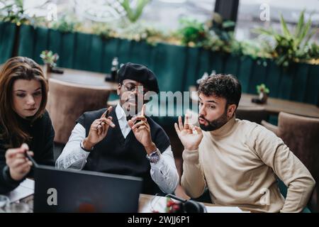 Groupe multiethnique de partenaires commerciaux travaillant ensemble dans un restaurant décontracté, utilisant un ordinateur portable et examinant des documents. Banque D'Images