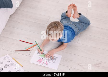 Petit garçon coloriage sur sol chaud à la maison. Système de chauffage Banque D'Images