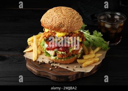 Délicieux hamburger avec patty de poulet croustillant et frites sur une table en bois noir Banque D'Images