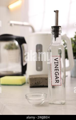 Bouilloire électrique de nettoyage. Bouteille de vinaigre et bicarbonate de soude dans un bol sur la table à l'intérieur Banque D'Images