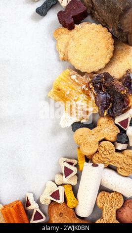 collection de diverses friandises et produits à mâcher pour chiens sur une surface grise tachetée avec espace de copie Banque D'Images