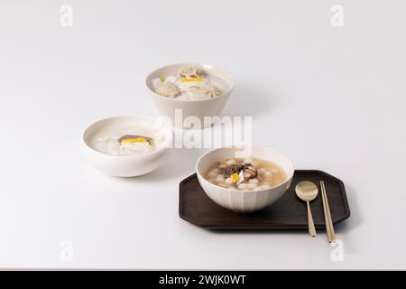 Sur une table blanche, trois bols de soupe de gâteau de riz ont été placés avec une cuillère Banque D'Images