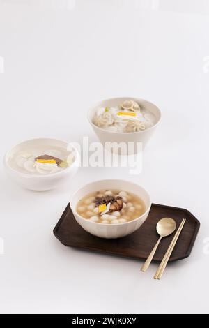 Sur une table blanche, trois bols de soupe de gâteau de riz ont été placés avec une cuillère Banque D'Images