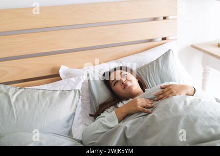 Jeune femme biraciale de taille plus se relaxant dans le lit à la maison, avec espace de copie inchangé Banque D'Images