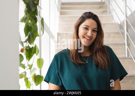 Jeune femme biracial plus grande taille sourit chaleureusement à l'intérieur, avec l'espace de copie inchangé Banque D'Images