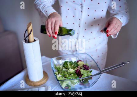 adolescente et sa mère en pyjama cuisinent et mangent une salade verte fraîche et de tomates ensemble Banque D'Images