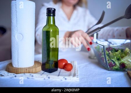 adolescente et sa mère en pyjama cuisinent et mangent une salade verte fraîche et de tomates ensemble Banque D'Images