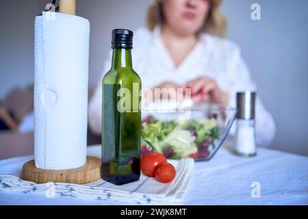 adolescente et sa mère en pyjama cuisinent et mangent une salade verte fraîche et de tomates ensemble Banque D'Images