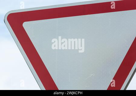 Panneau de signalisation contre le ciel. Triangle blanc avec bordure rouge. Signal, céder. Jour d'été. Banque D'Images