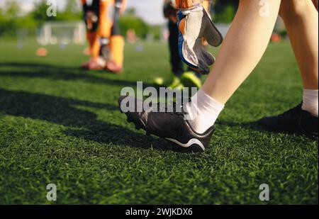 Académie des gardiens de but de football. Gardien de but de football étirant les jambes lors de la séance d'entraînement. Garçon dans des crampons de football et des gants dans la session de pratique Banque D'Images