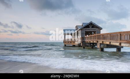 Jetée en bois, située à Key West, Floride, s'étendant dans les eaux tropicales calmes de l'océan, au lever du soleil. Il y a un soupçon d'orange dans le ciel Banque D'Images