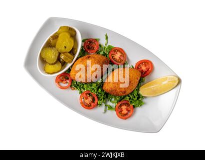 Kibbeh ou icli kofte sur une assiette en porcelaine blanche avec cornichons et salade Banque D'Images