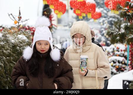 Deux filles asiatiques marchant sur fond de décorations du nouvel an chinois dans la ville d'hiver Banque D'Images