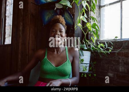 Jeune femme noire en tenue colorée sourit à la caméra en riant Banque D'Images
