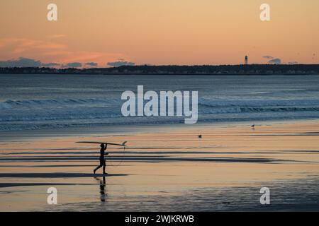 Surfeur silhouette marchant avec planche de surf sur la plage Banque D'Images