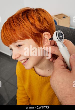 Examen auditif des enfants. Pédiatre examinant l'enfant mâle roux avec otoscope Banque D'Images