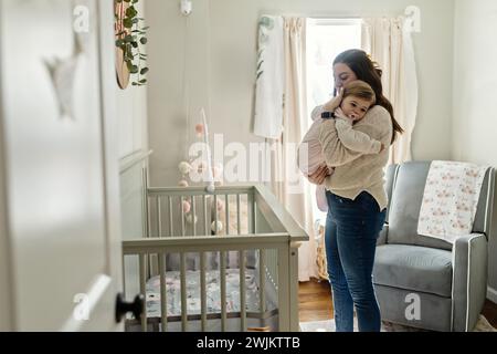 Mère tenant bébé prêt à la poser pour une sieste Banque D'Images