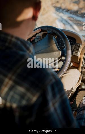 Au-dessus de l'épaule d'un homme conduisant un VUS dans la boue. Banque D'Images