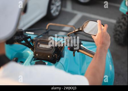 Personne réglant le rétroviseur sur le véhicule tout-terrain à quatre roues dans le stationnement Banque D'Images