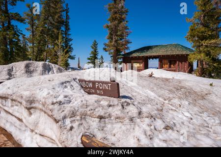 Panneau Rainbow point dans le parc national du canyon Bryce, couvert par une grande quantité de neige, journée chaude de printemps, ciel bleu clair. Cabane de repos à proximité. Grands arbres. Banque D'Images