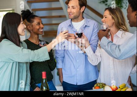 Groupe d'amis griller avec des verres à vin tout en accrochant à l'intérieur Banque D'Images