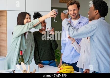 Groupe d'amis griller avec des verres à vin tout en accrochant à l'intérieur Banque D'Images